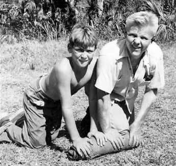Boy and man rolling up tent