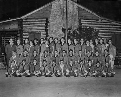 Troop lined up in front of flag pole. Basketball court was installed after WW II.